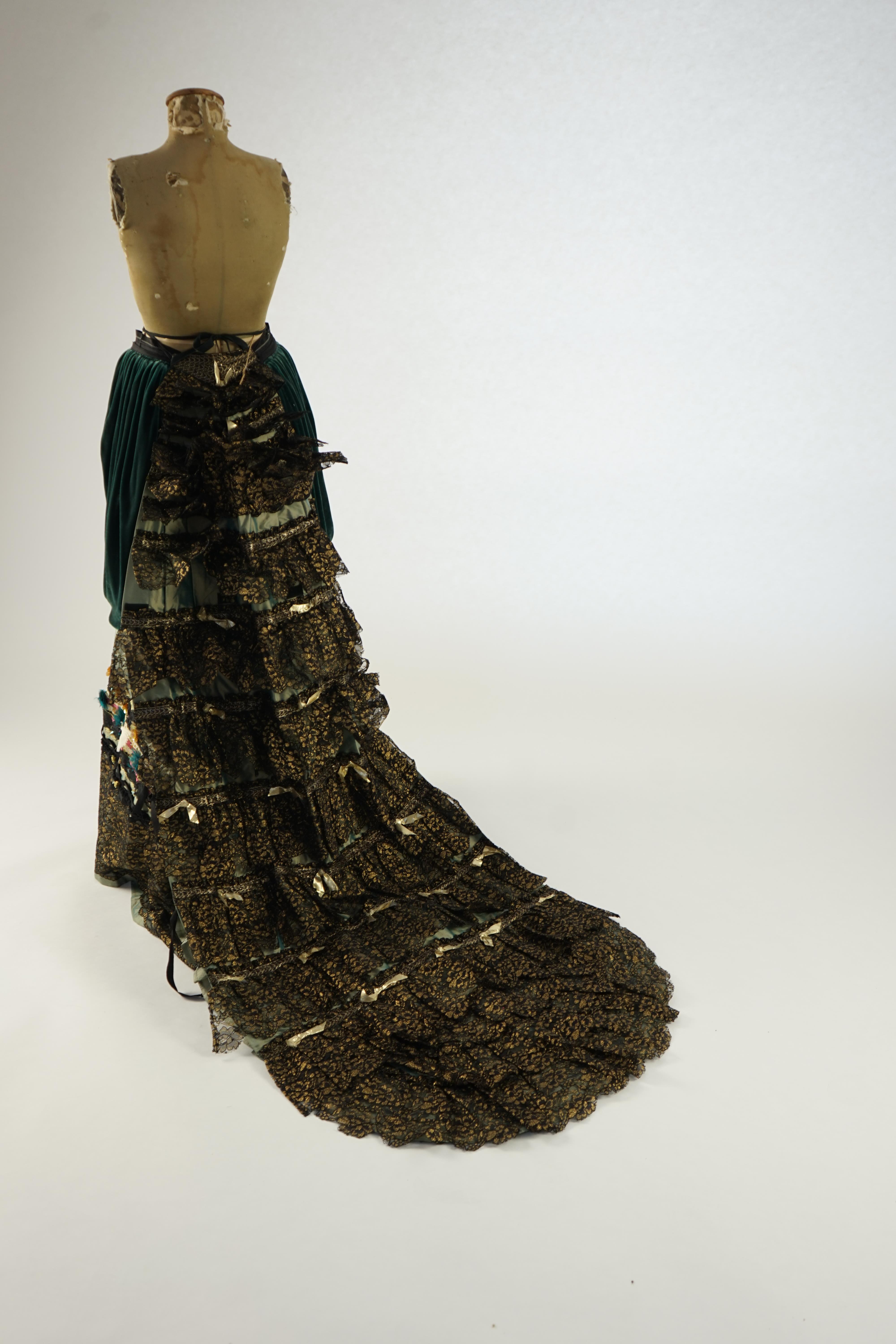 An Edwardian style lady's green taffeta skirt decorated with beaded, sequinned, ribboned border and swags of silk velvet, together with matching train layered with frilled black and gold lace, appliquéd with gold bows